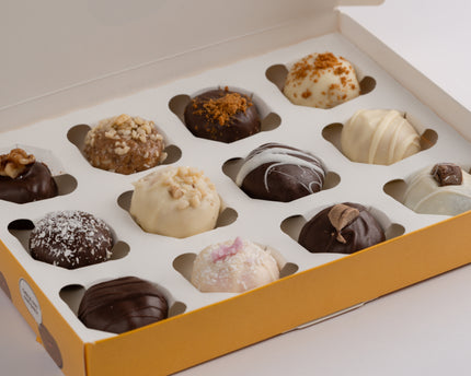 A box of 12 protein balls with various toppings and coatings, presented in a yellow box.