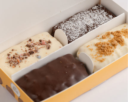 A box of four Loada Balls protein bars in a variety of flavors, each topped with different ingredients such as chocolate chips and coconut flakes.