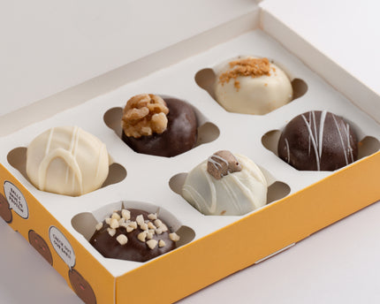 A box of six Loada Balls protein balls with various toppings, packaged in a yellow box.