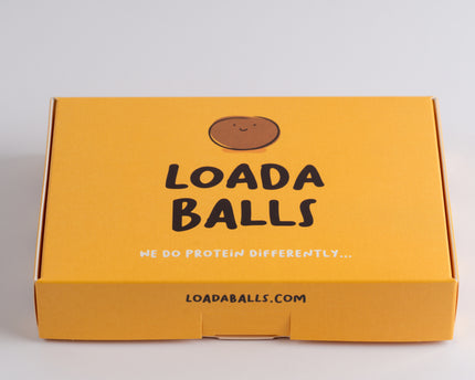 A yellow box of Loada balls protein bars with the brand's logo and website URL on the top.