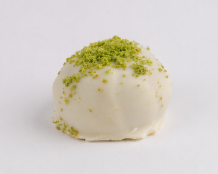 Loada Balls White Pistachio Protein ball close up with a grey background.